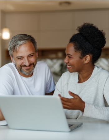 Midlife couple working together on a laptop, highlighting the importance of Split It or Share It: Navigating Finances and Relationships in Midlife.